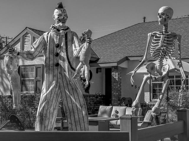 A scary clown decoration holds up fake children.