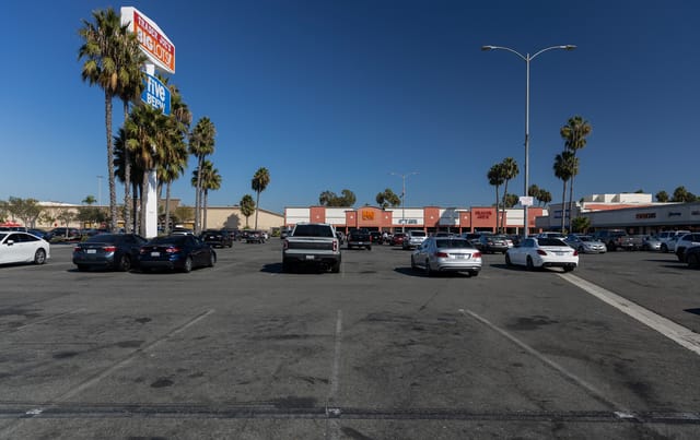 Pictured are cars and empty parking spaces in a large not near storefronts.