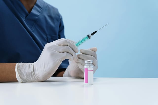 A person holds a syringe filled with green liquid.