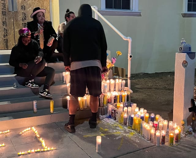 Four people sit and stand around dozens of burning candles.