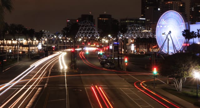 Time lapse photo of the red and white stripes made by cars driving down an street at night.