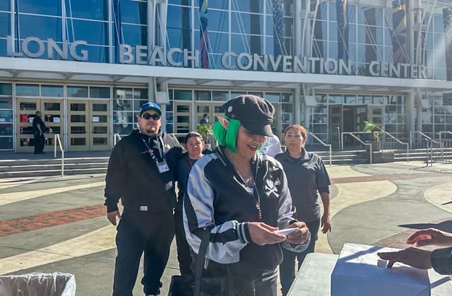 People stand outside a glassy building labeled “Long Beach Convention Center.”