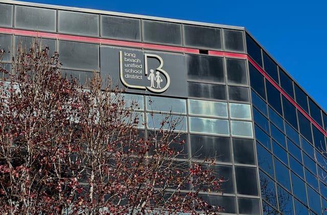 A tree stands in front of a glassy building labeled “long beach unified school district.”