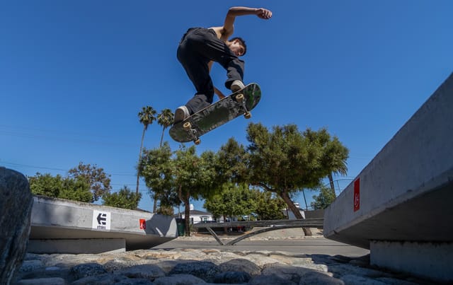 A young person flies through the air on a skateboard.