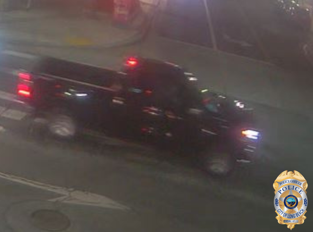 Blurry photo of a black truck at night.