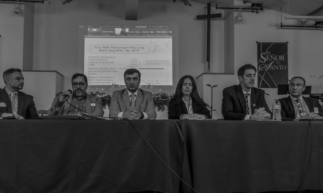 Black and white photo of six people sitting side by side at a table.