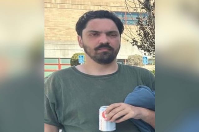 A man wearing a green shirt and holding a can of soda