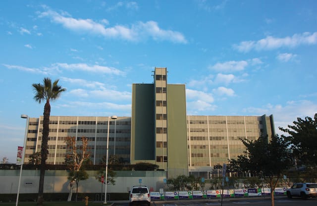A large building set against a blue sky with wispy white clouds.