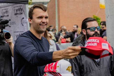 A man in blue shirt holds out a red baseball cap.