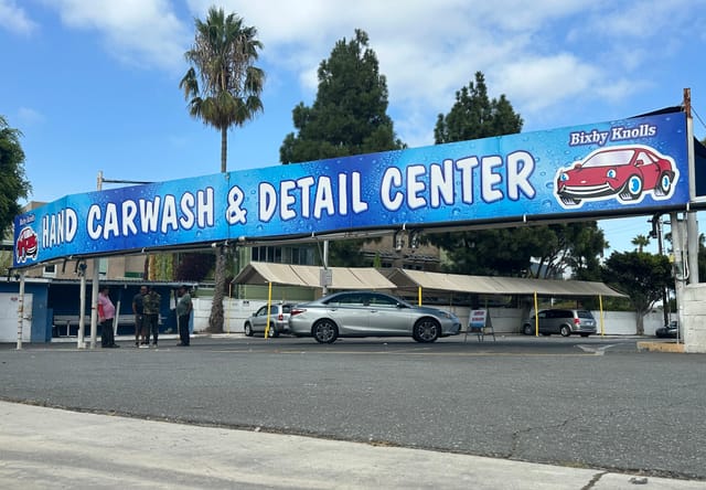 Blue car wash sign saying "Bixby Knolls Hand Carwash & Detail Center."