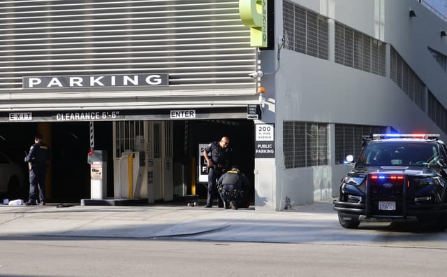Three police officers and a police car are outside a parking garage